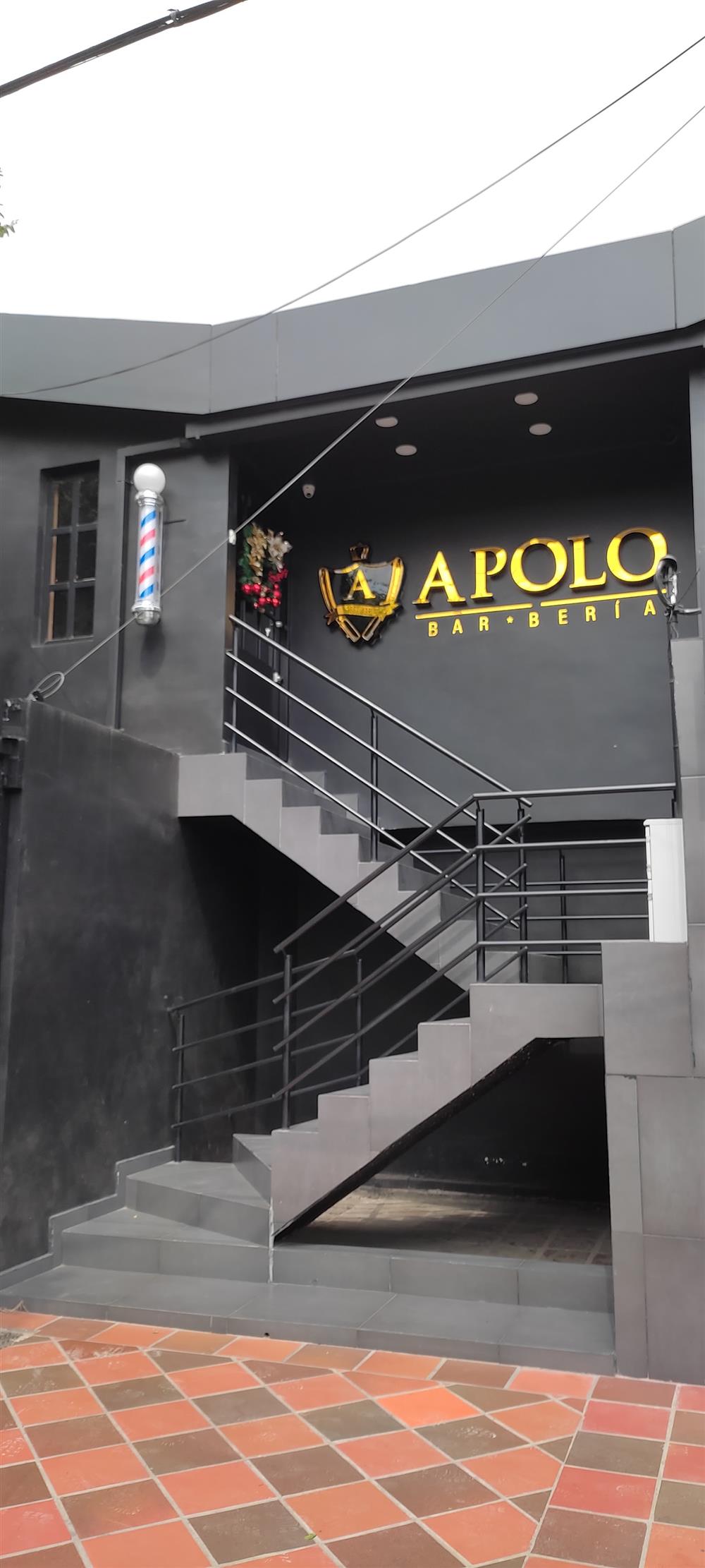 Escaleras hacia el segundo piso con el letrero dorado de Apolo